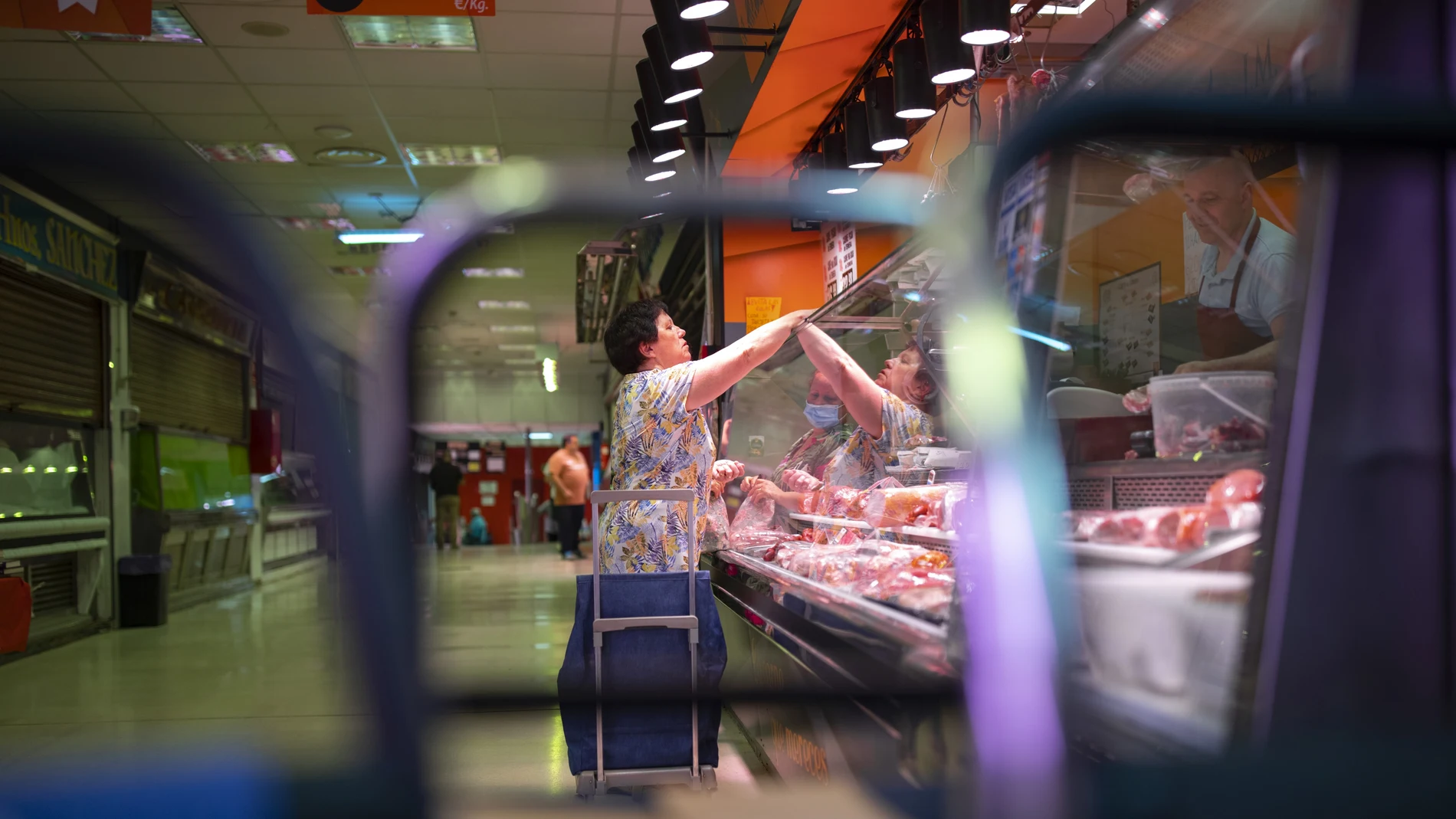 Mujer pagando en una carnicería de un mercado 