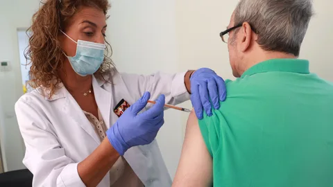 Una sanitaria pone una vacuna a un hombre