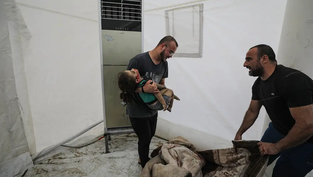 A man carries the body of a child at Al Shifa hospital after an air strike in Gaza City, 17 October 2023.