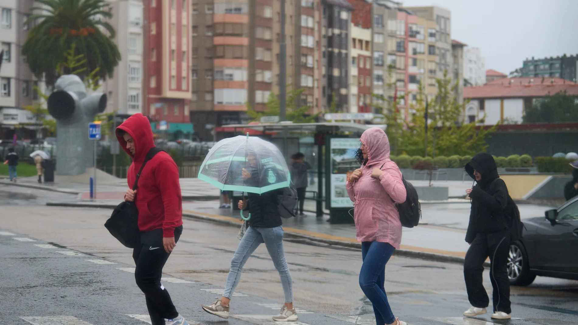 Varias personas se cubren de la lluvia y el viento con paraguas.