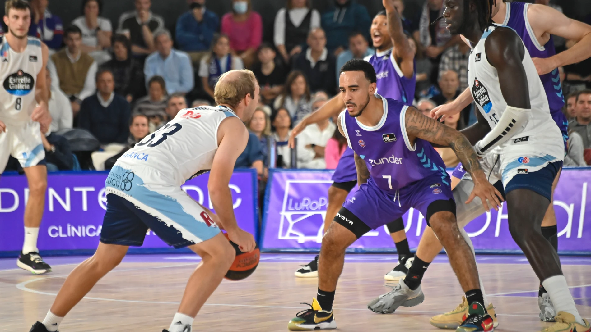 El base estadounidense del Zunder Palencia Brandon Brown (c) defiende al base estadounidense del Breogán Conner Frankamp (i), durante el partido de Liga Endesa de baloncesto que se disputa este sábado en el Pabellón Municipal de Palencia