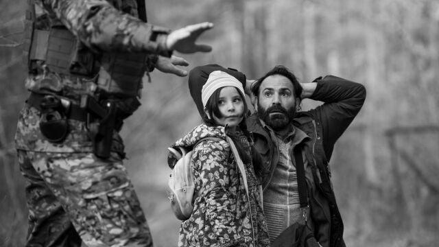 Escena del filme con Jalal Altawil (de rodillas), que da vida a un refugiado que intenta pasar de la frontera bielorrusa a la polaca junto a su familia