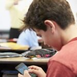 Niño con teléfono móvil en clase.