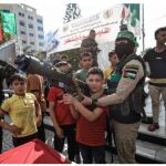 Terrorista de Hamas muestra a un niño el funcionamiento de un lanzagranadas