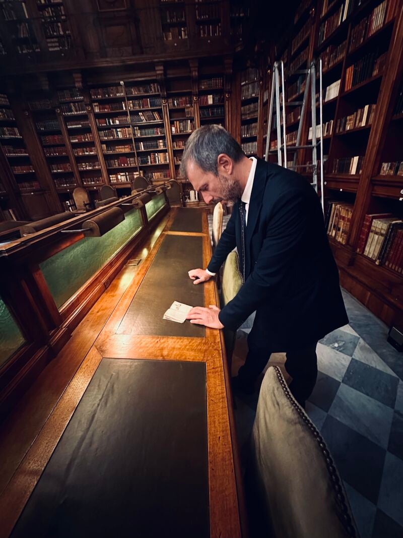 Francesco Malfetano observando el libro más pequeño de la biblioteca