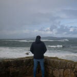 Una persona observa el mar con olas por rl temporal causado por la borrasca Domingos, en la playa de A Lanzada