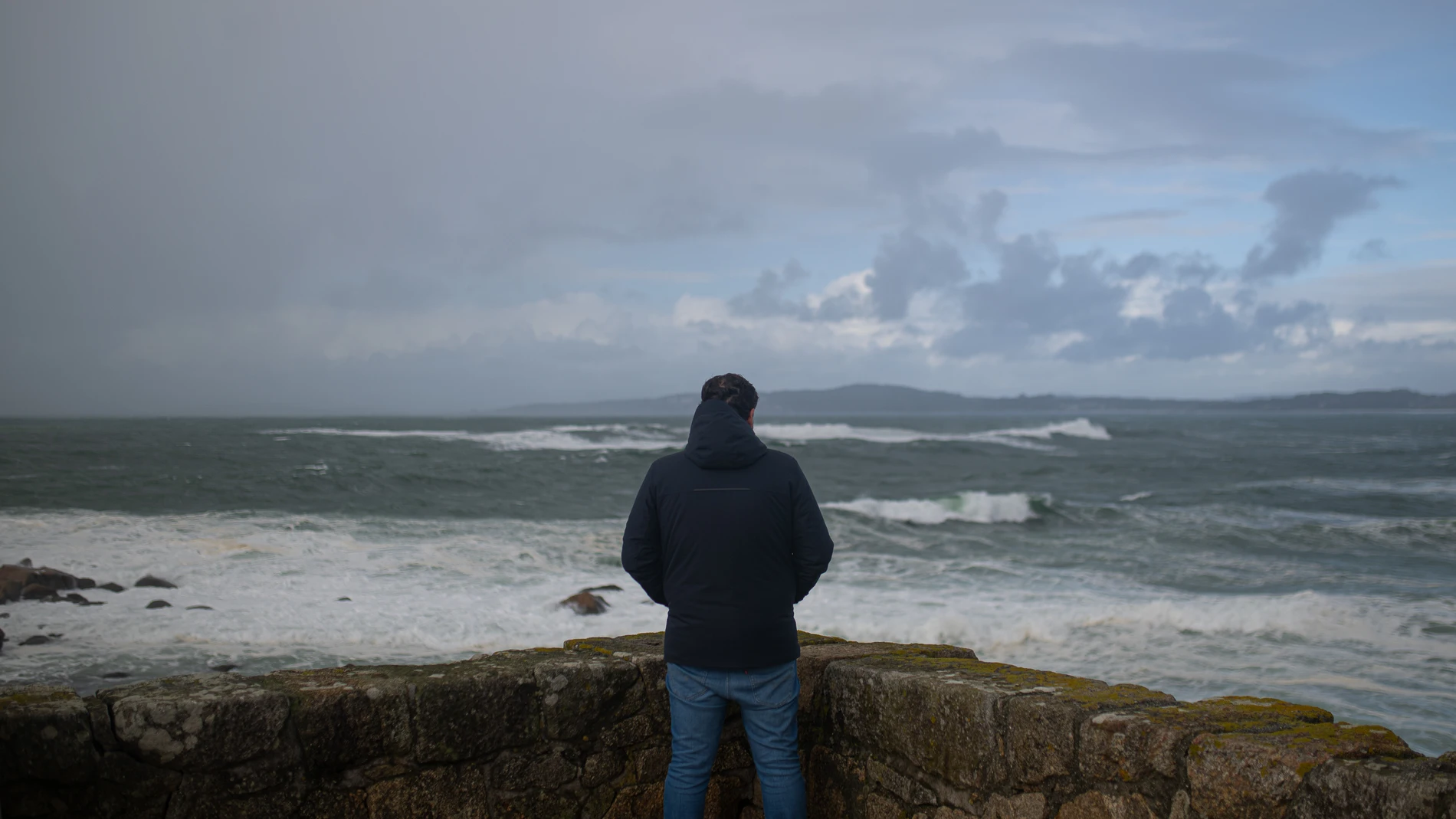 Una persona observa el mar con olas por rl temporal causado por la borrasca Domingos, en la playa de A Lanzada