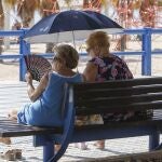 Dos mujeres se protegen del sol y de calor con abanico y parasol durante este miércoles en el que se viven altas temperaturas en este inicio de Otoño. 