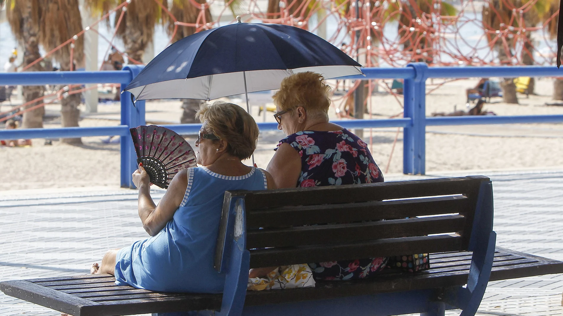 Dos mujeres se protegen del sol y de calor con abanico y parasol durante este miércoles en el que se viven altas temperaturas en este inicio de Otoño. 
