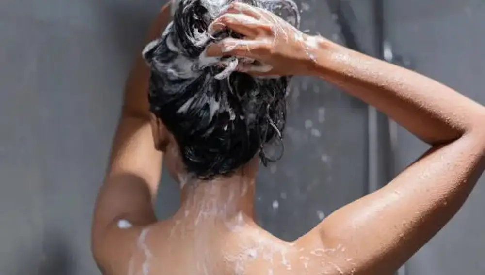 Una joven se enjabona el pelo en la ducha