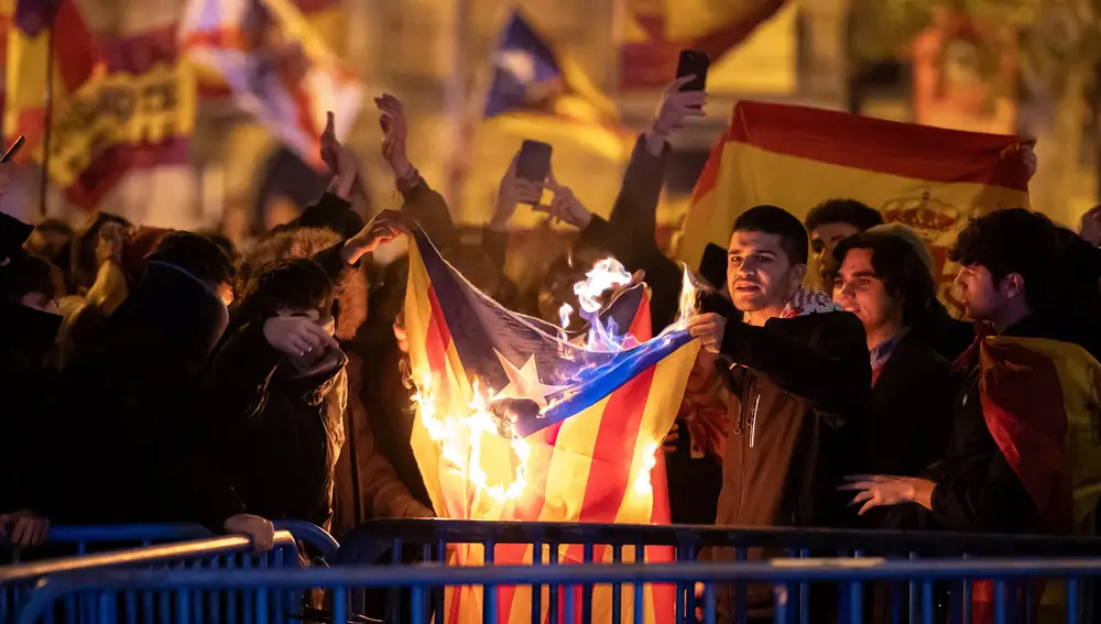 Decenas de manifestantes queman una bandera estelada, durante una manifestación contra la amnistía frente a la sede del PSOE en Ferraz.