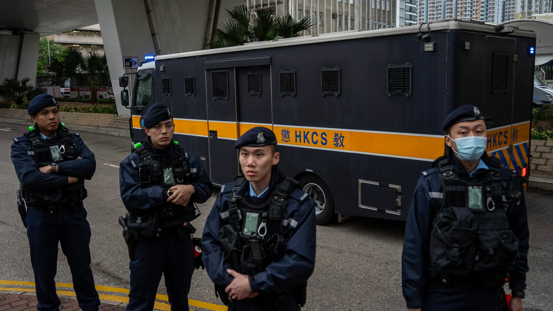 Police officers stand guard as an armored prison van carrying activist publisher Jimmy Lai leaves West Kowloon Magistrates' Courts, where Lai's trial is scheduled to open, in Hong Kong, Monday, Dec. 18, 2023. (AP Photo/Vernon Yuen)