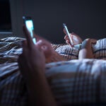Pareja mirando el teléfono móvil en la cama