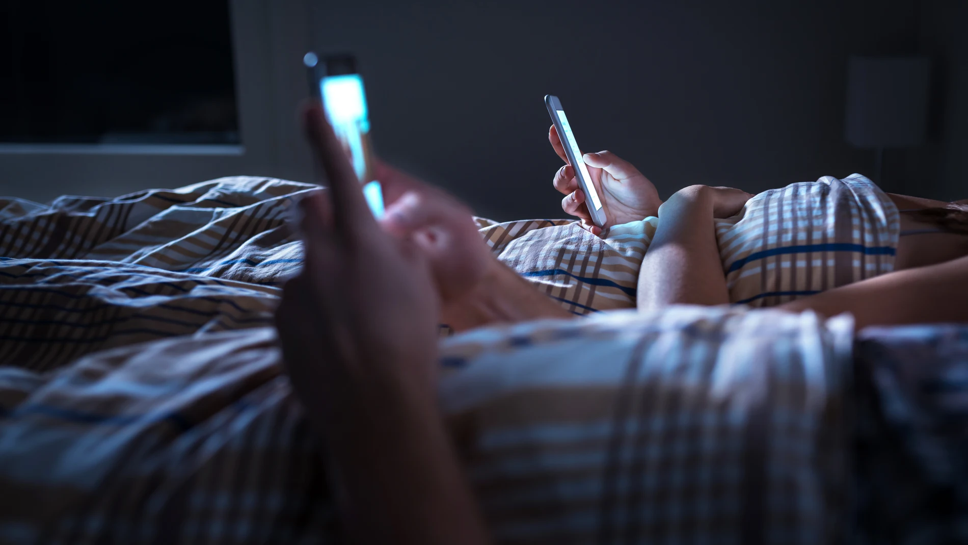 Pareja mirando el teléfono móvil en la cama