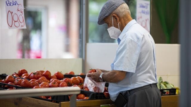 Imagen de una persona mayor comprando en una fruteria.
