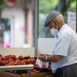Imagen de una persona mayor comprando en una fruteria.