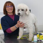 La veterinaria Marian Belloso en su clínica junto a un paciente y diversos suplementos alimenticios que evitan el estrés animal