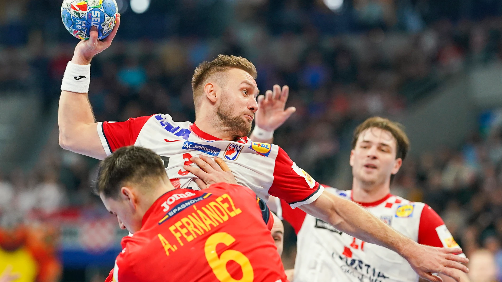 Croatia's Luka Cindric, center, battles for the ball with Spain's Angel Fernandez Perez during the Handball European Championship preliminary round match between Spain and Croatia at the SAP Arena in Mannheim, Germany, Friday, Jan. 12, 2024. (Uwe Anspach/dpa via AP)