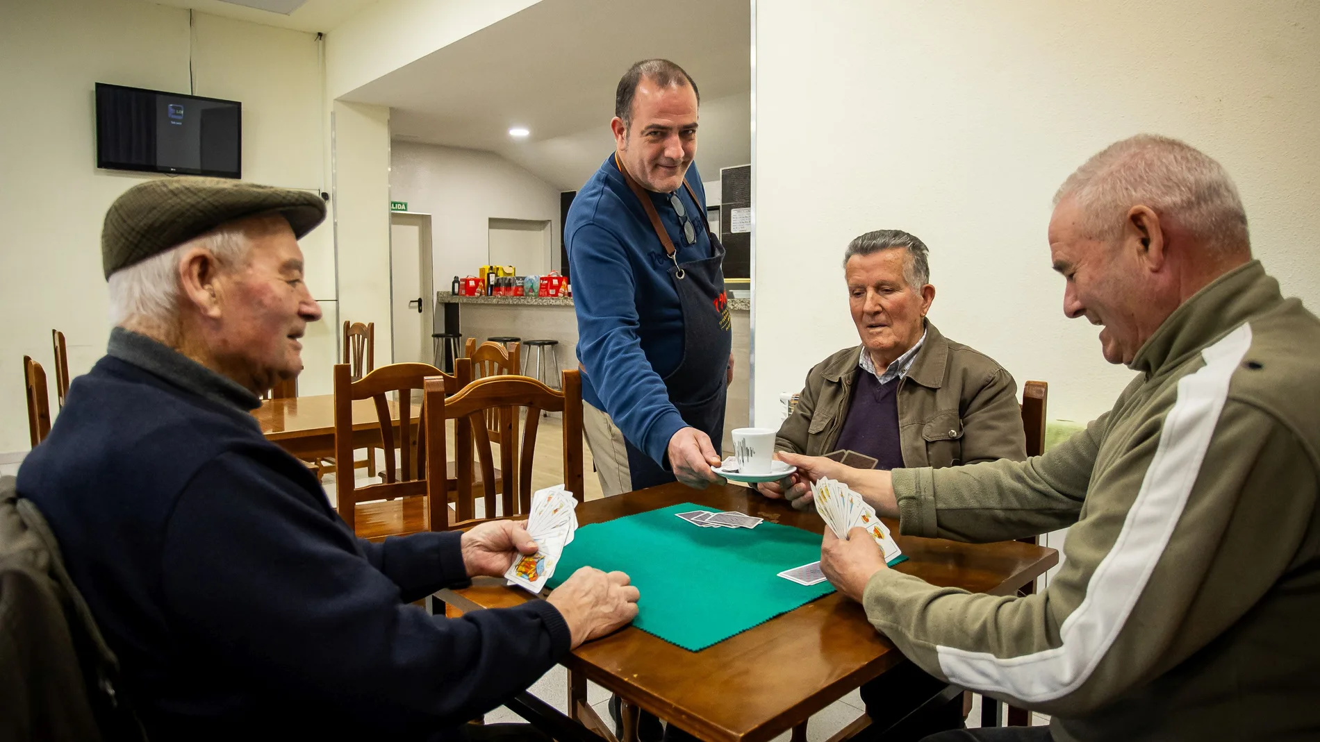 Ricardo Arnal, del bar de Sepulcro Hilario, sirve a sus clientes que juegan la partida