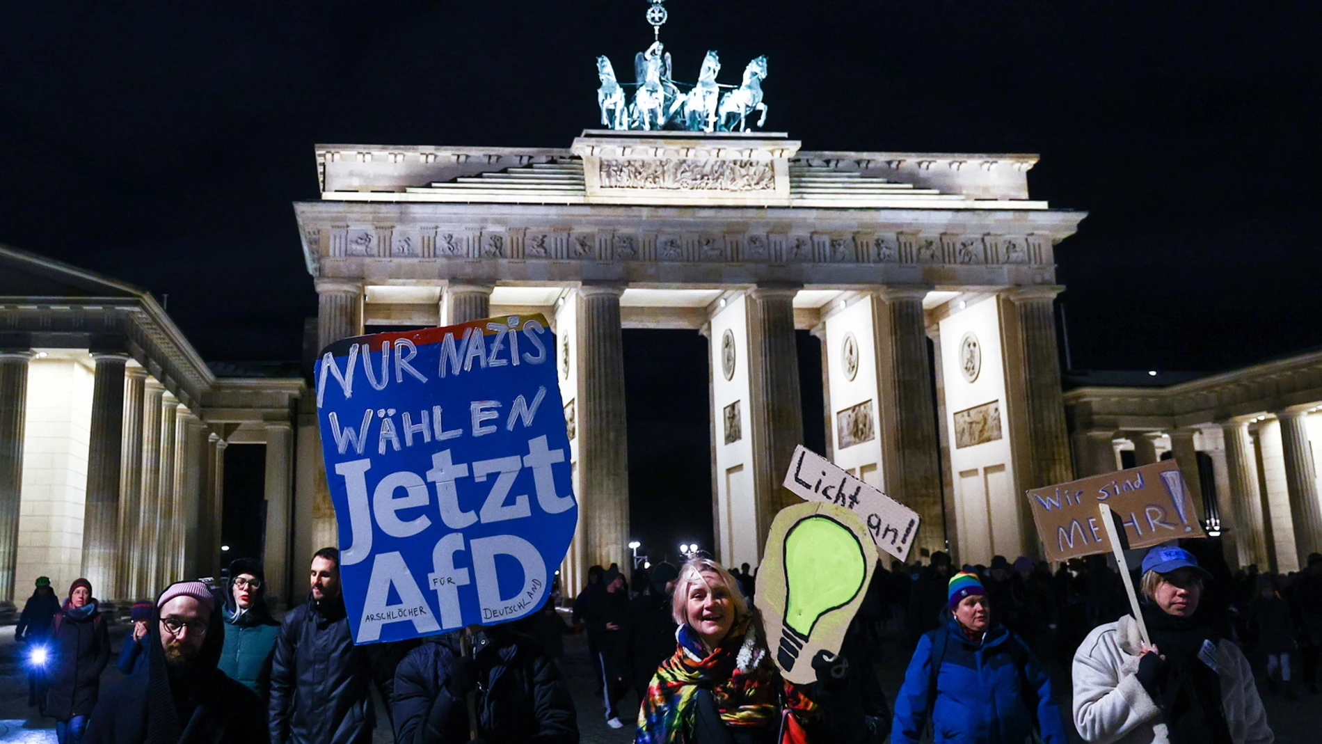 Berlin (Germany), 21/01/2024.- Protesters hold signs reading 'only Nazis elect AFD now' (L), 'light on' (C) and 'we are more' (R) as they walk in front of Brandenburg Gate as attend a demonstration against the far-right Alternative for Germany (AfD) party in Berlin, Germany, 21 January 2024. The protest held under the slogan 'Defend Democracy', was organized by the Fridays for Future movement, along with other non-governmental organizations, as a reaction to revelations of the investigative j...