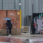 Dos migrantes se protegen de la lluvia con un paraguas en las inmediaciones del centro de Emergencia, Acogida y Derivación en el Acuartelamiento 'Primo de Rivera', donde se alojan migrantes procedentes de Canarias, en Alcalá de Henares.