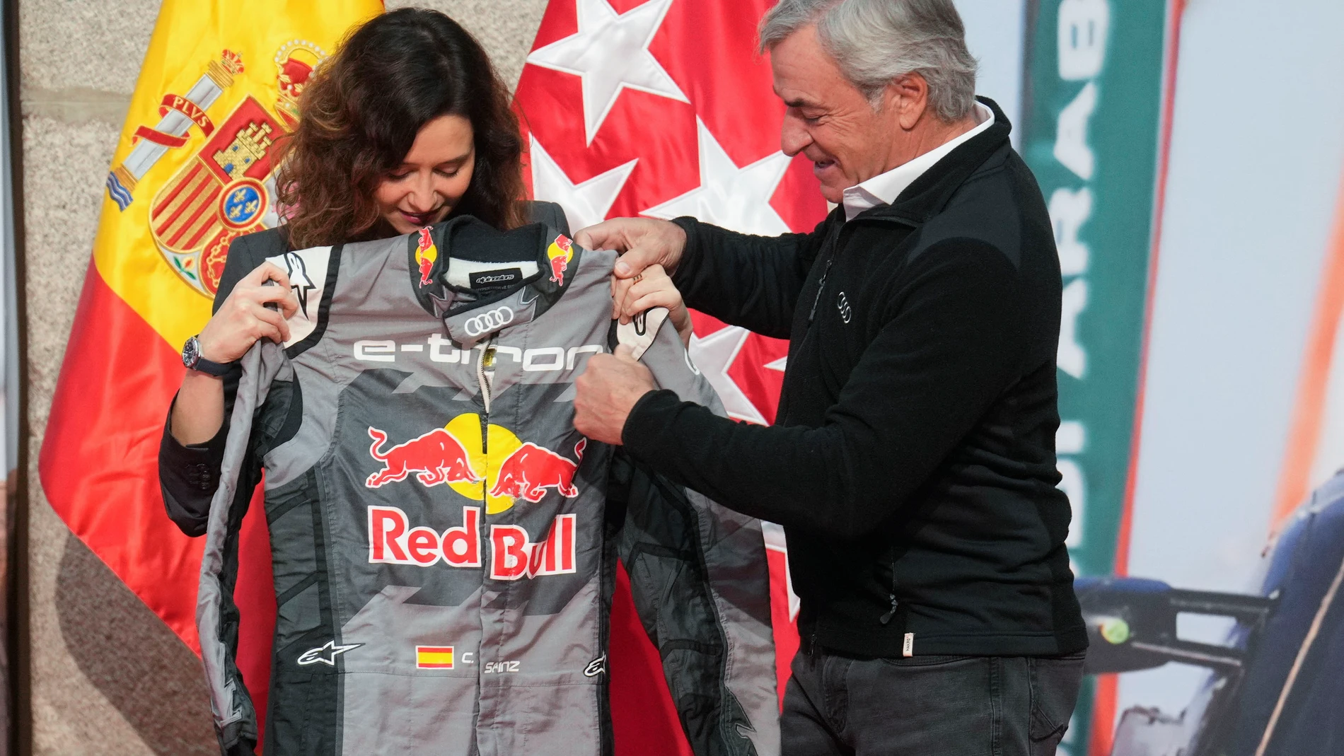 MADRID, 02/02/2024.- La presidenta de la Comunidad de Madrid, Isabel Día Ayuso, recibe un traje de piloto en la recepción a los ganadores del Rally Dakar 2024, Carlos Sáinz (d) y Lucas Cruz, este viernes en la sede del Gobierno regional, en la puerta de El Sol. EFE/ Borja Sánchez Trillo