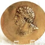 Moneda con la efigie de Filipo II, un hombre que perdió un ojo en la guerra. A la derecha, el arca que se supone que custodia sus restos en Vergina
