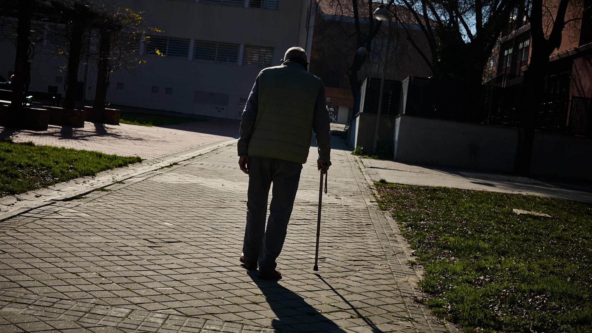 Mayores jubilados de la tercera edad pasean y toman el sol en un parque de Madrid.