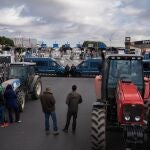 Agentes de Mossos d'Esquadra delante de los agricultores y tractores que han cortado uno de los accesos a Mercabarna, a 13 de febrero de 2024, en Barcelona, Catalunya (España). 