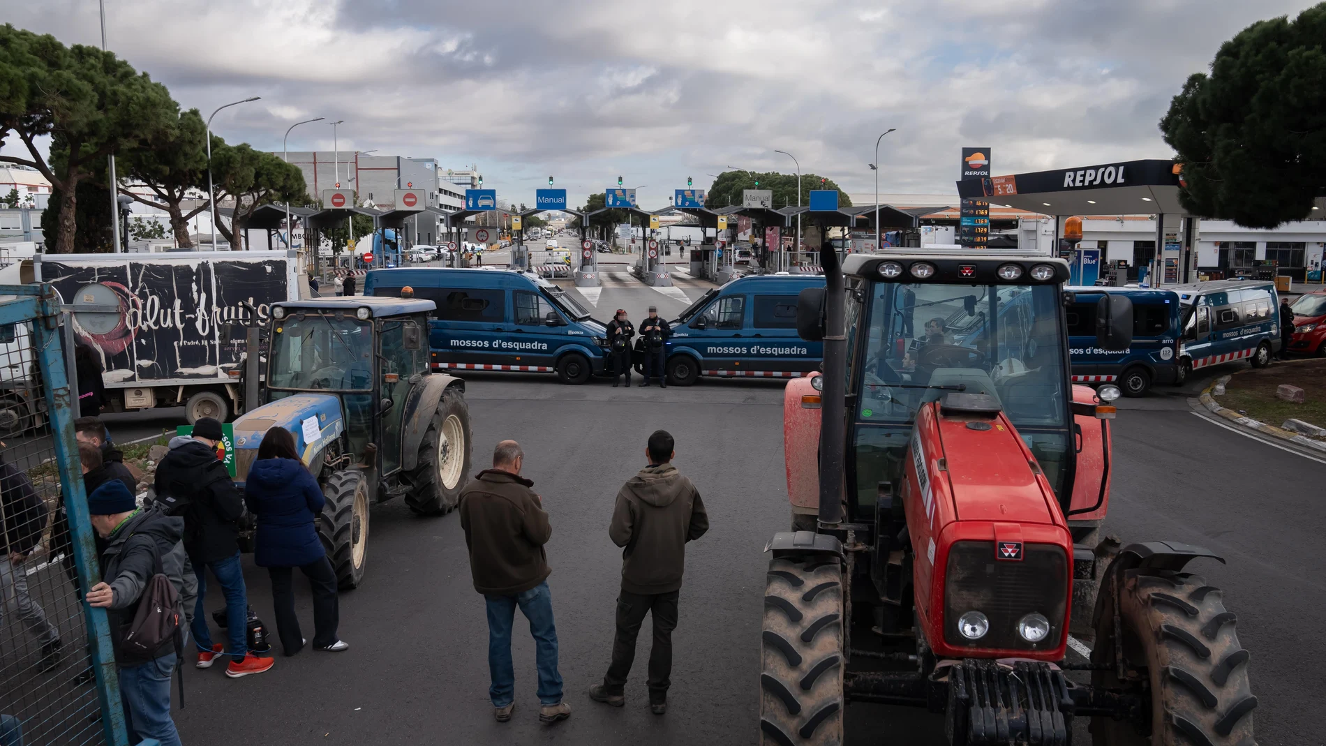 Agentes de Mossos d'Esquadra delante de los agricultores y tractores que han cortado uno de los accesos a Mercabarna, a 13 de febrero de 2024, en Barcelona, Catalunya (España). 