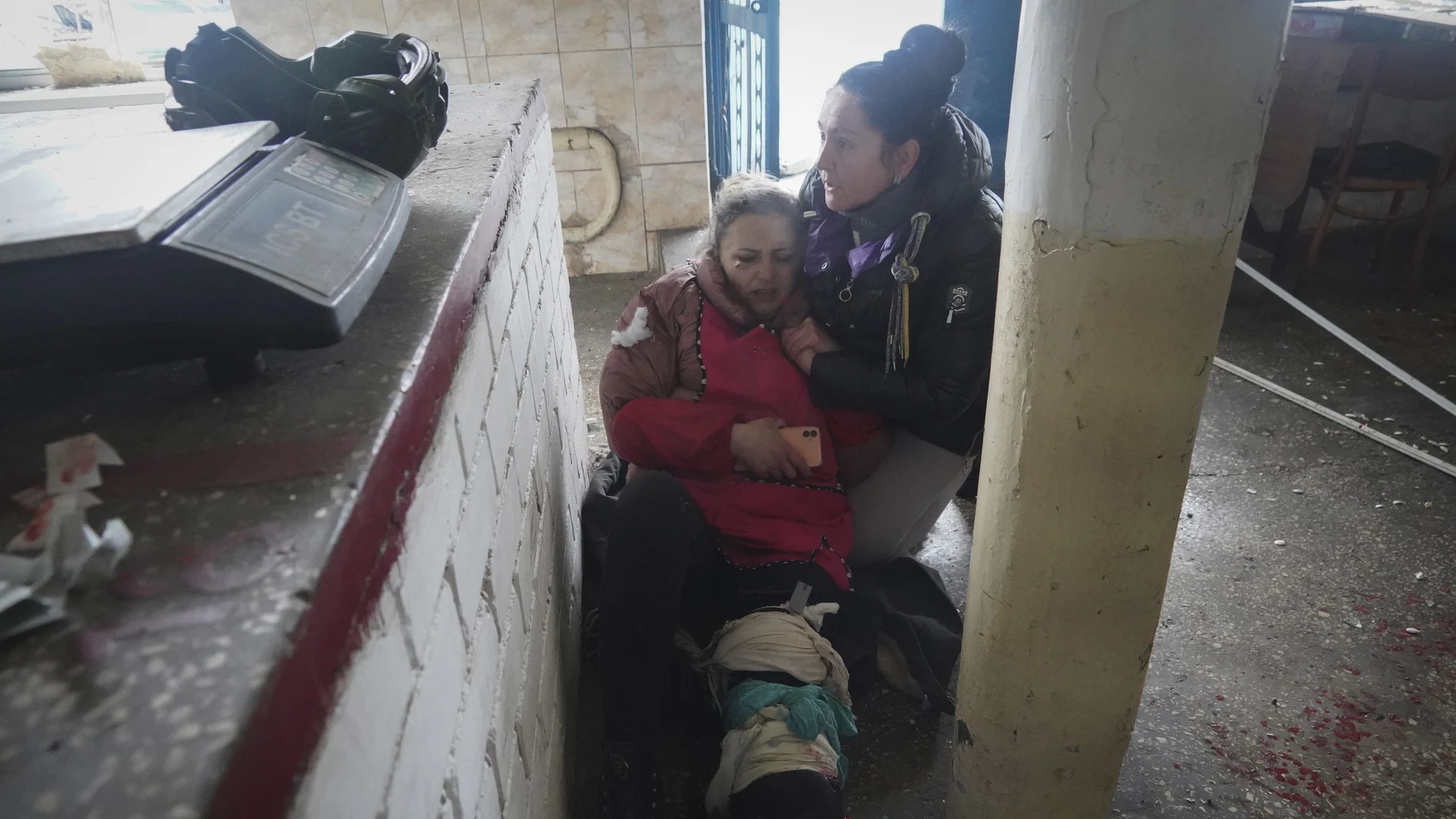 Una mujer socorre a una herida en los bombardeos rusos en Jarkiv