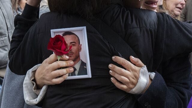 Una familiar sostiene una foto de uno de los agentes fallecidos a la salida del funeral