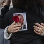 Una familiar sostiene una foto de uno de los agentes fallecidos a la salida del funeral