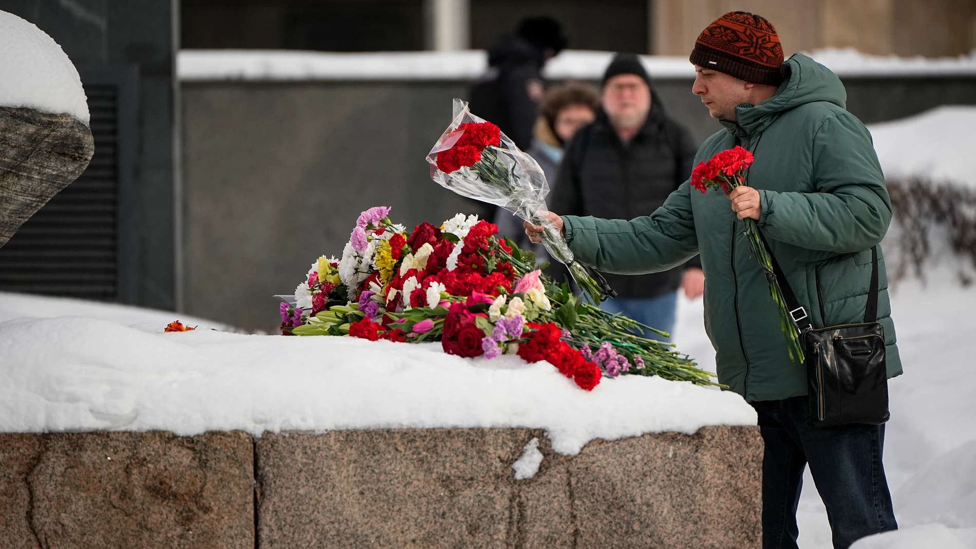 A man lays flowers to pay the last respect to Alexei Navalny at the monument, a large boulder from the Solovetsky islands, where the first camp of the Gulag political prison system was established, near the historical the Federal Security Service (FSB, Soviet KGB successor) building in Moscow, Russia, on Sunday, Feb. 18, 2024. Russians across the vast country streamed to ad-hoc memorials with flowers and candles to pay tribute to Alexei Navalny, the most famous Russian opposition leader and t...