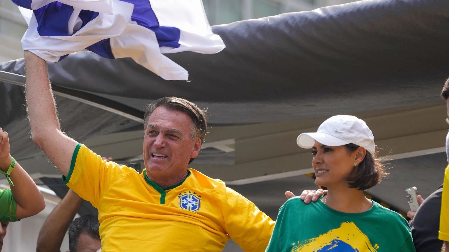 Former President Jair Bolsonaro waves a flag as he addresses supporters, accompanied by his wife Michelle, in Sao Paulo., Brazil, Sunday, Feb. 25, 2024. Bolsonaro and some of his former top aides are under investigation into allegations they attempted plotted a coup to remove his successor, Luis Inacio Lula da Silva. (AP Photo/Andre Penner)