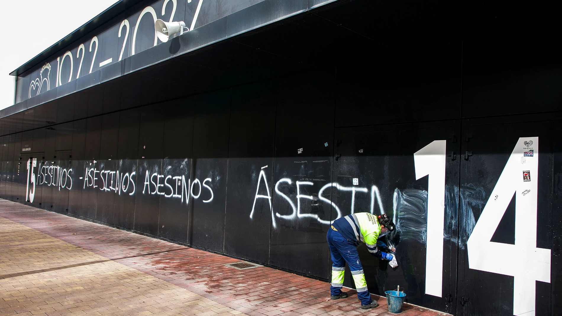 Trabajadora eliminando las pintadas de "asesinos" en la fachada del Estadio Municipal El Plantío (del Burgos CF)