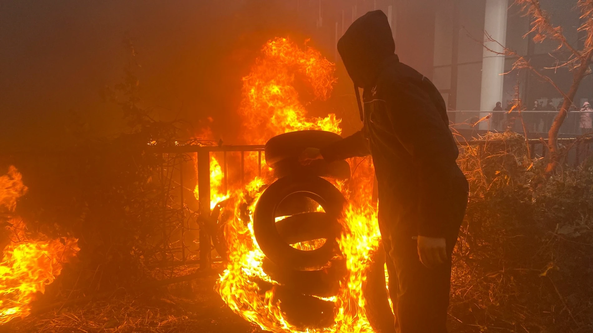 BRUSELAS, 26/02/2024.- Un hombre quema una pira de neumáticos a pocos metros de la sede del Consejo Europeo, durante la movilización de agricultores. Varias decenas de tractores entraron a primera hora de este lunes en el centro histórico de Bruselas, incluida la Grand Place, haciendo sonar sus bocinas, mientras que se espera que otros cientos que avanzan hacia la capital tomen el barrio europeo coincidiendo con la reunión de ministros europeos de Agricultura. EFE/Paula García-Ajofrín
