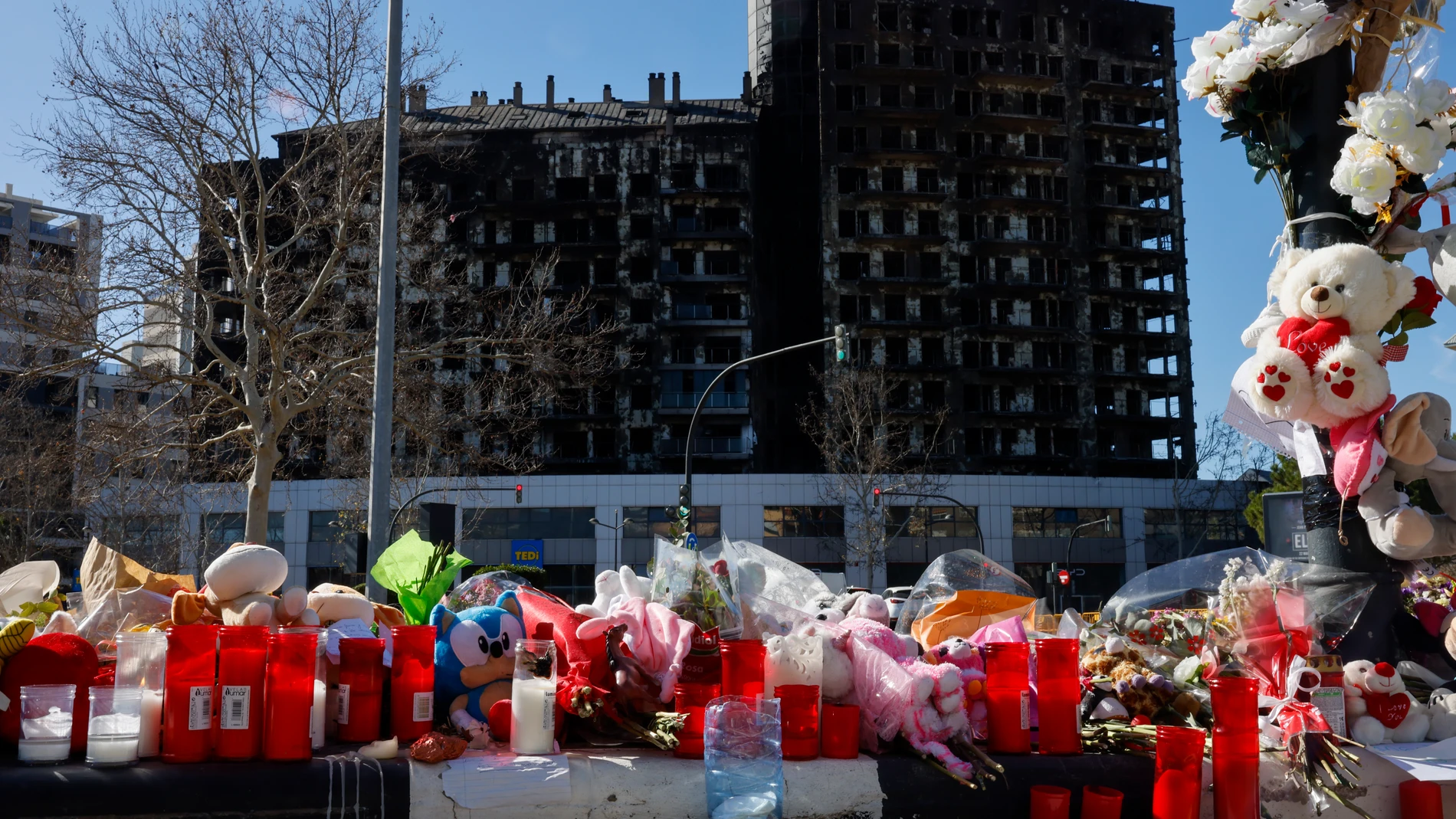 GRAFCVA8852. VALENCIA, 29/02/2024.- Detalle de flores, velas y peluches colocados a modo de homenaje ante el edificio incendiado en el barrio de Campanar de València en el que murieron diez personas y deja más de 400 damnificados. EFE/Ana Escobar 