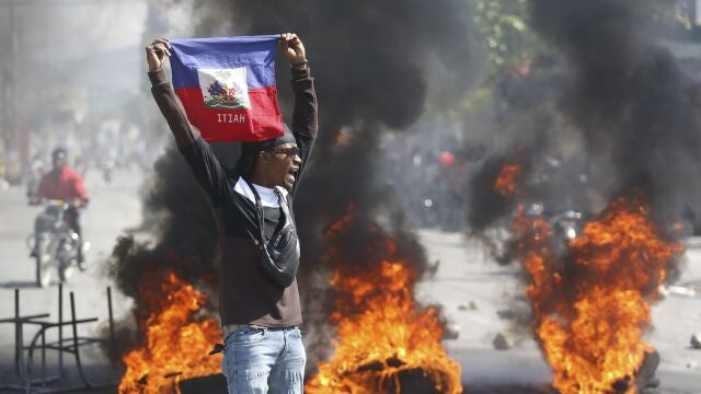 A demonstrator holds up an Haitian flag during protests demanding the resignation of Prime Minister Ariel Henry in Port-au-Prince, Haiti, Friday, March 1, 2024. 
