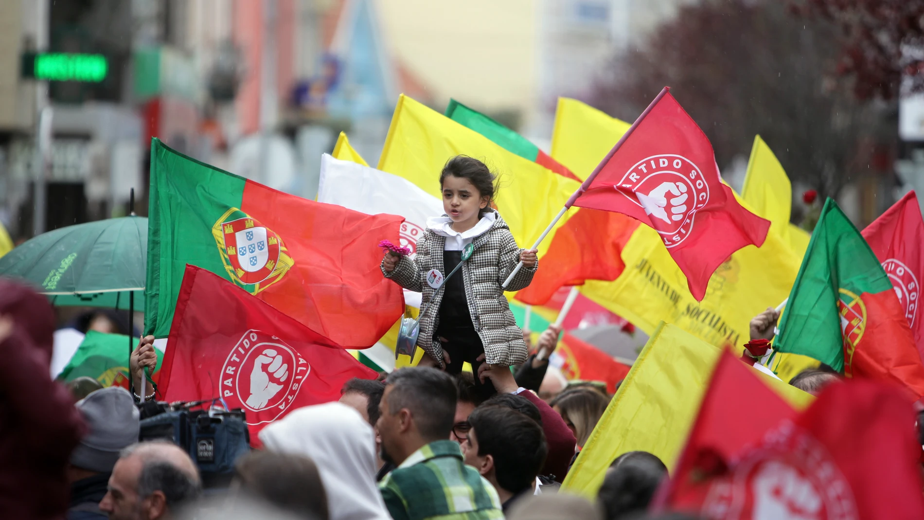 A child holding a flower and a Socialist Party flag is lifted above the crowd during an election campaign action with the Socialist Party leader Pedro Nuno Santos on the street in the Lisbon suburb of Moscavide, Friday, March 8, 2024. Portugal is holding an early general election on Sunday when 10.8 million registered voters elect 230 lawmakers to the National Assembly, the country's Parliament. (AP Photo/Joao Henriques)