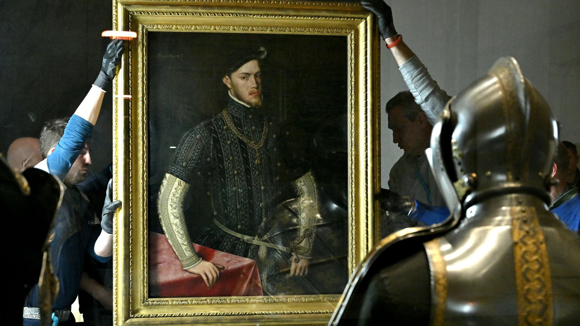 Algunos operarios colocan la primera obra invitada a la Galería de las Colecciones Reales, el «Retrato de Felipe II», pintado por Antonio Moro