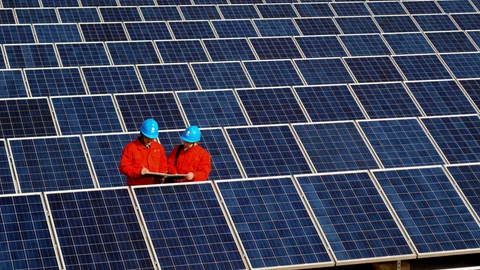 Workers check solar panels at a solar power station on a factory roof in Changxing, eastern China's Zhejiang province.