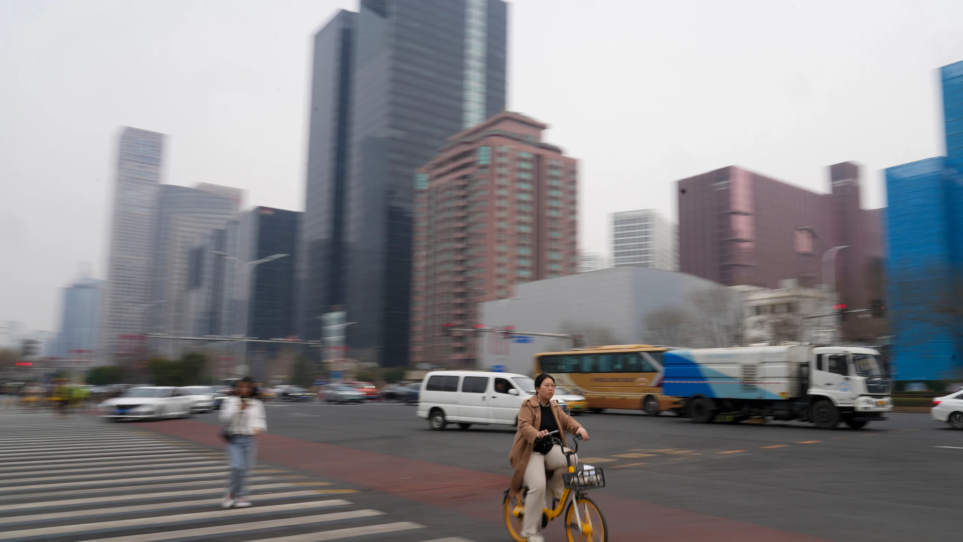 A cyclist rides near the main business district in Beijing, China, Saturday, March 23, 2024. (AP Photo/Tatan Syuflana)