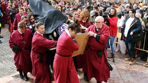 Penitentes la Cofradía del Santo Cristo del Desenclavo de León protegen la talla de la lluvia