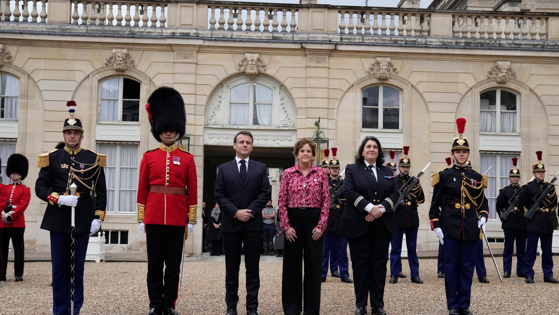French President Emmanuel Macron and British ambassador to France Menna Rawlings, right left, pose at the Elysee Palace, Monday, April 8, 2024 in Paris. Sixteen soldiers from No 7 Company Coldstream Guards and 32 members of the Gendarmerie Garde Republicaine mount guard at the Elysee palace as British troops join French guards in a special ceremony at the Elysee Palace to celebrate 120 years of "entente cordiale" between the longtime rival powers. (AP Photo/Thibault Camus, Pool)