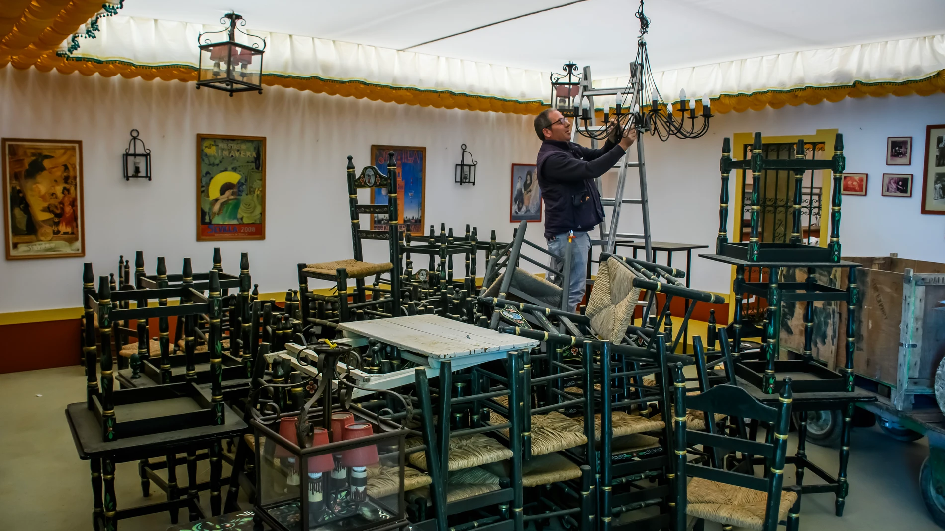 GRAFAND376. SEVILLA, 09/04/2024.- Un hombre coloca una lámpara en una de las casetas del recinto de la Feria de Abril de Sevilla, que arranca el próximo fin de semana. EFE/ Raúl Caro