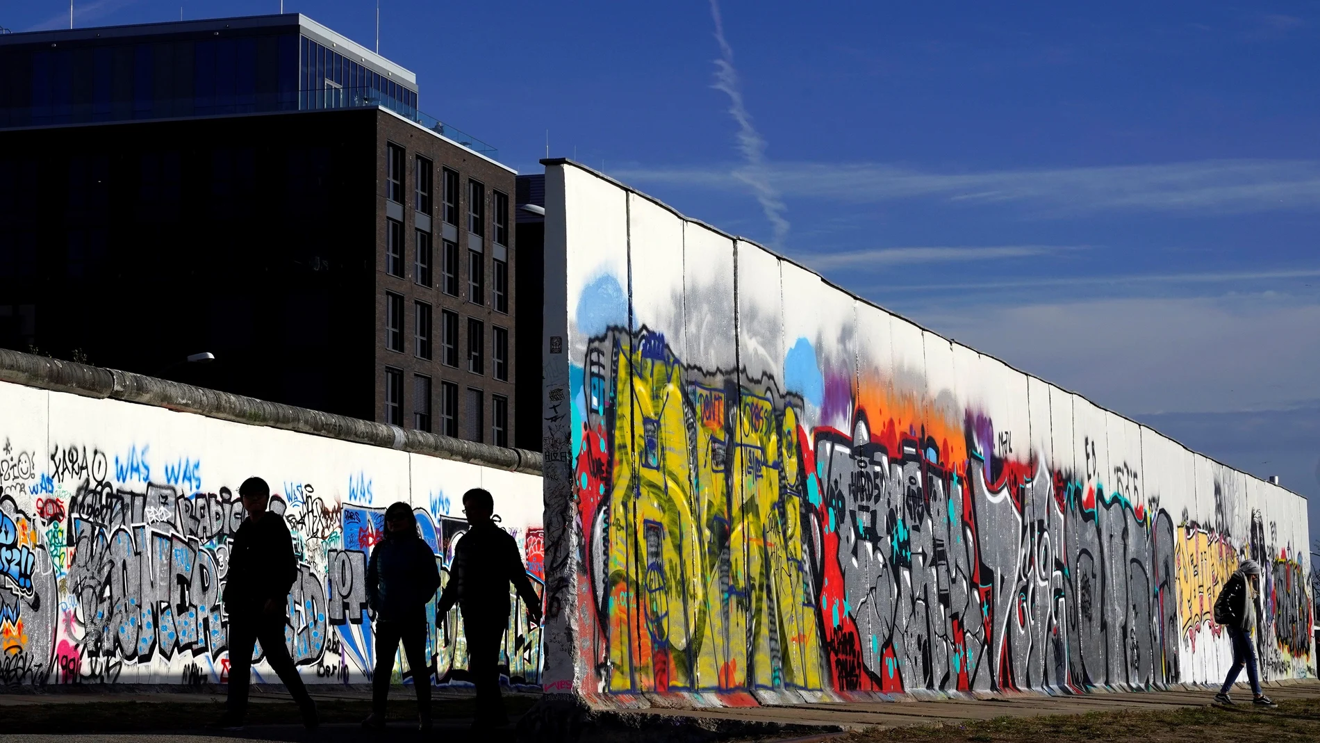 Varias personas caminan junto a la East Side Gallery, el más largo tramo que queda en pie del muro, en Berlín, Alemania.
