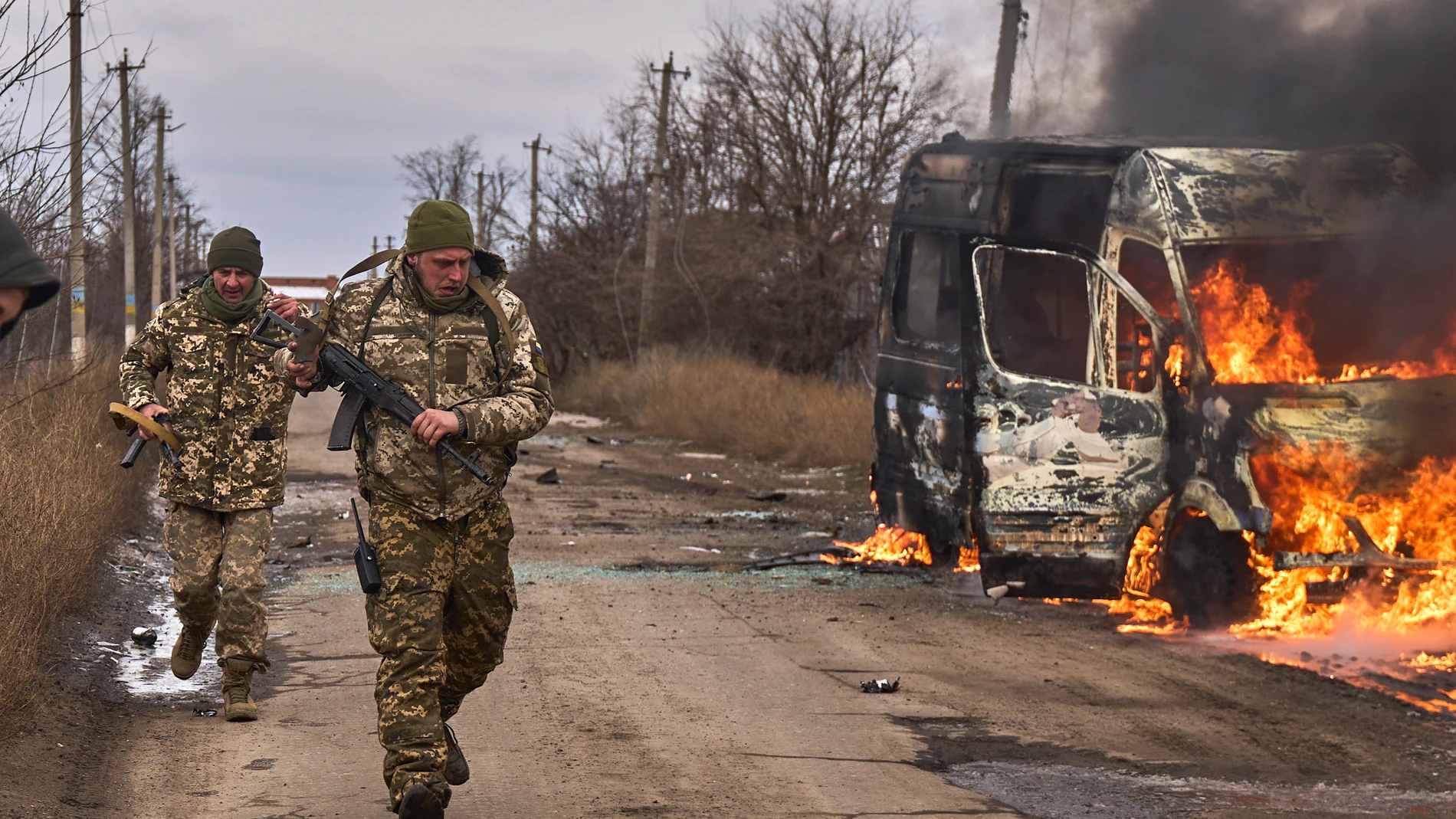 FILE - In this photo provided by the Ukrainian 10th Mountain Assault Brigade "Edelweiss", Ukrainian soldiers pass by a volunteer bus burning after a Russian drone hit it near Bakhmut, Donetsk region, Ukraine, Thursday, Nov. 23, 2023. Ukraine’s parliament has passed a controversial law that will govern how the country recruits new soldiers to replenish depleted forces who are increasingly struggling to fend off Russian troops. (Shandyba Mykyta, Ukrainian 10th Mountain Assault Brigade "Edelweis...