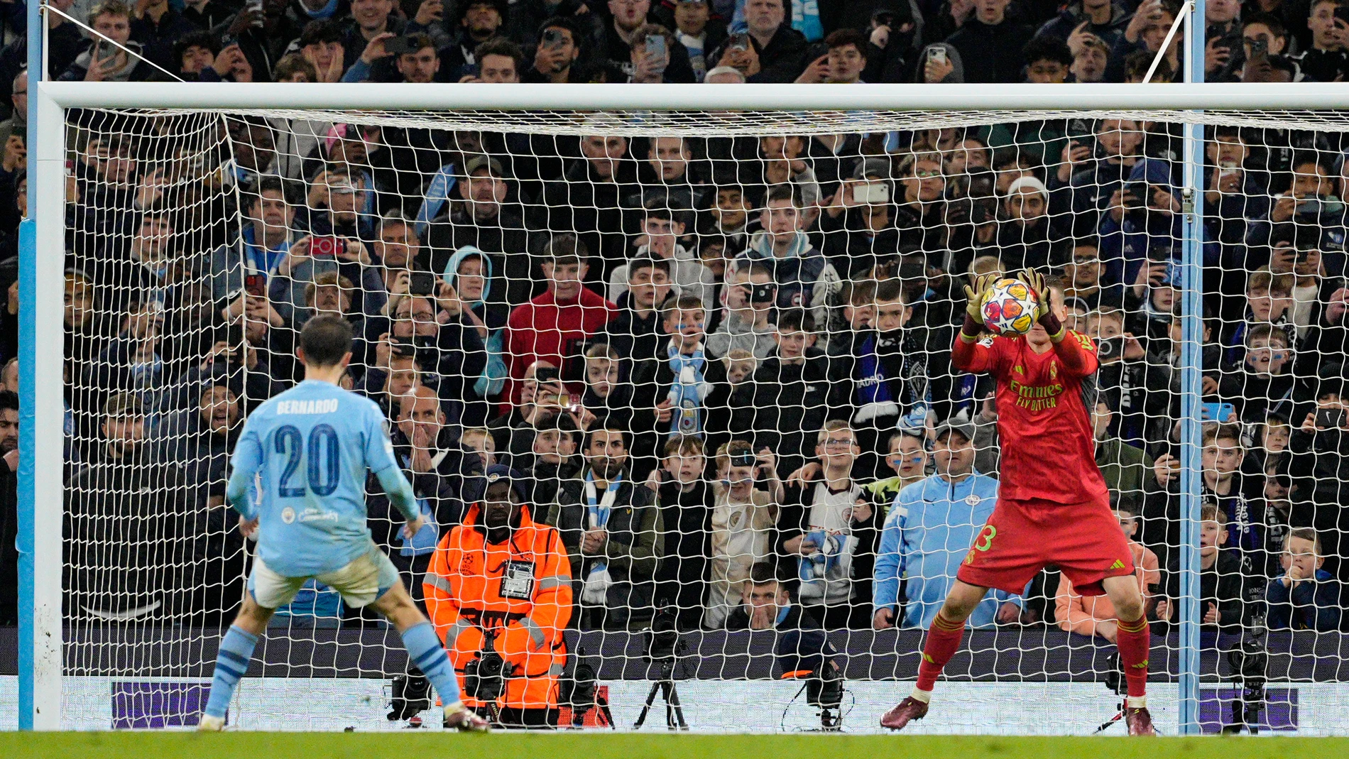 Real Madrid's goalkeeper Andriy Lunin, right, saves a penalty by Manchester City's Bernardo Silva during a shootout during the Champions League quarterfinal second leg soccer match between Manchester City and Real Madrid at the Etihad Stadium in Manchester, England, Wednesday, April 17, 2024. (AP Photo/Dave Shopland)