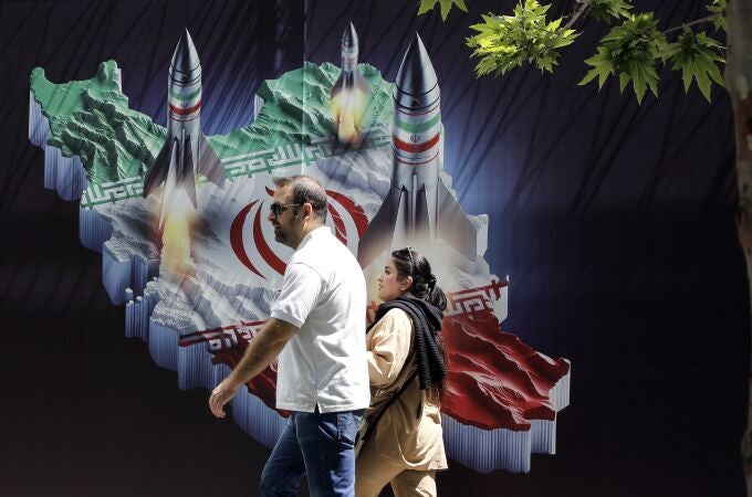 An Iranian couple walk past a huge anti-Israeli banner carrying pictures of missiles on Iran's map, in Tehran, Iran, 19 April 2024. Iranian state media reported that three aerial objects were destroyed by air defense systems over the central city of Isfahan early morning on 19 April. 